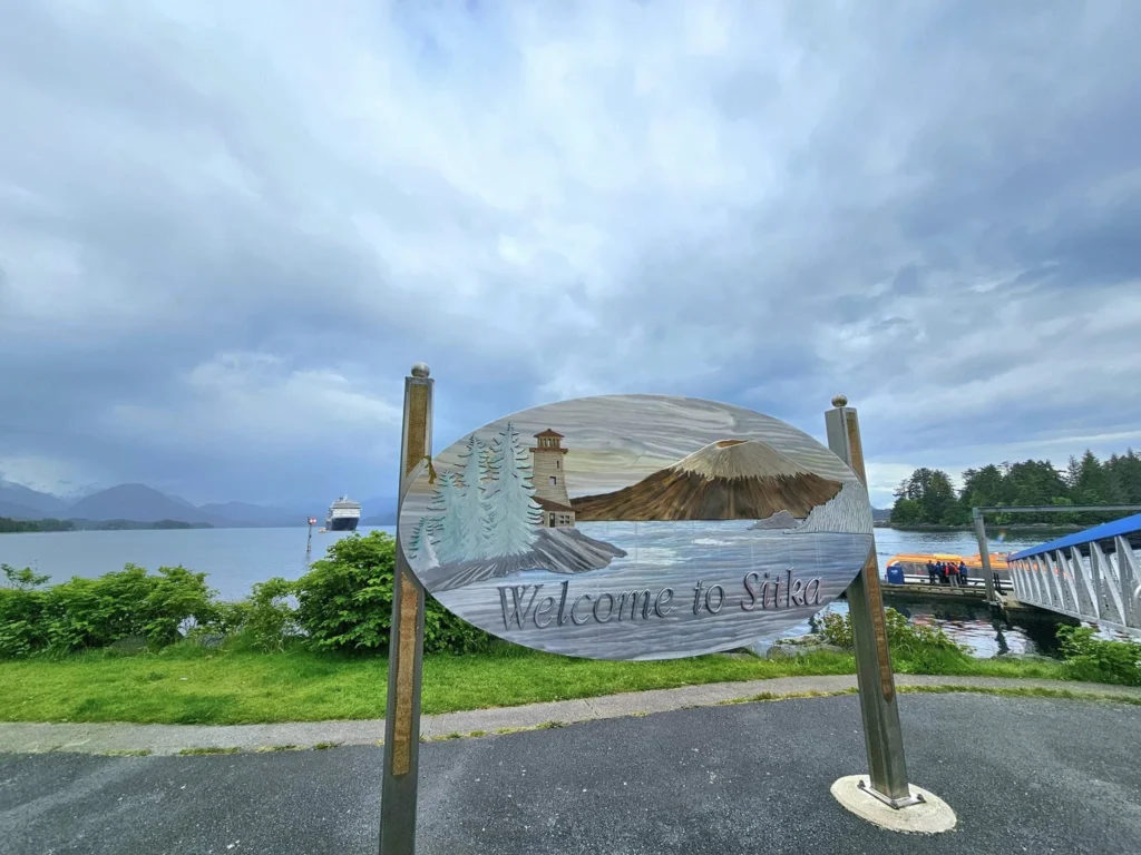 Cruising with Danny and Peter, Holland America Line, Westerdam, Sitka, Alaska, United States | Biking the scenic Sitka Cross Trail through lush Alaskan forests, capturing Sitka's natural beauty and outdoor adventure; a whale breaching in Whale Park, showcasing Sitka Alaska's wildlife; a majestic eagle soaring above, symbolizing the rich wildlife; and an intricate Tlingit totem pole representing the cultural heritage of Sitka, Alaska, all set against the stunning coastal landscape of this Alaskan gem.