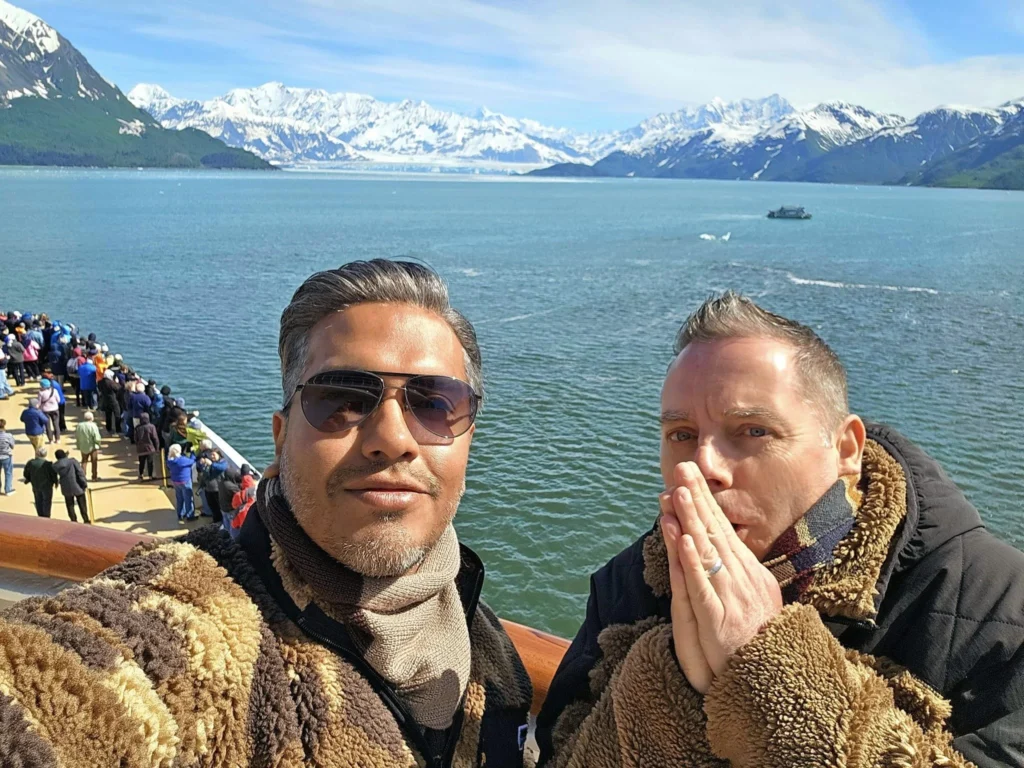 Cruising with Danny and Peter, Holland America Line, Westerdam, Hubbard Glacier, Alaska, United States | View of Hubbard Glacier from the boat during an unforgettable tour, showcasing stunning blue ice and calm Arctic waters. Thrilling ice calving event captures large chunks of ice breaking off and crashing into the water. Mirror-like reflection of the glacier on still waters highlights its majestic blue hues. A delightful picnic with the glacier in the background combines delicious food with breathtaking views, while a close-up of the glacier's intricate ice formations shows deep crevasses and jagged edges.
