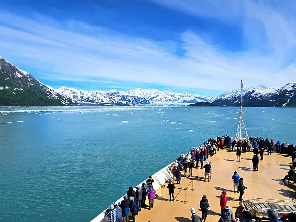 Cruising with Danny and Peter, Holland America Line, Westerdam, Hubbard Glacier, Alaska, United States | View of Hubbard Glacier from the boat during an unforgettable tour, showcasing stunning blue ice and calm Arctic waters. Thrilling ice calving event captures large chunks of ice breaking off and crashing into the water. Mirror-like reflection of the glacier on still waters highlights its majestic blue hues. A delightful picnic with the glacier in the background combines delicious food with breathtaking views, while a close-up of the glacier's intricate ice formations shows deep crevasses and jagged edges.