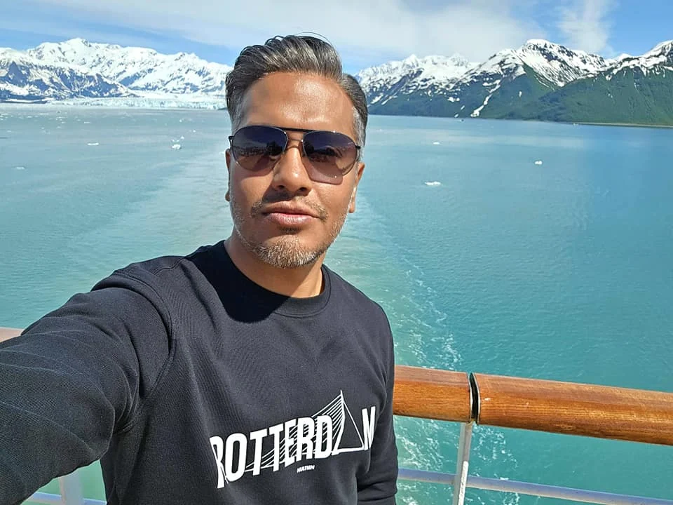 Cruising with Danny and Peter, Holland America Line, Westerdam, Hubbard Glacier, Alaska, United States | View of Hubbard Glacier from the boat during an unforgettable tour, showcasing stunning blue ice and calm Arctic waters. Thrilling ice calving event captures large chunks of ice breaking off and crashing into the water. Mirror-like reflection of the glacier on still waters highlights its majestic blue hues. A delightful picnic with the glacier in the background combines delicious food with breathtaking views, while a close-up of the glacier's intricate ice formations shows deep crevasses and jagged edges.