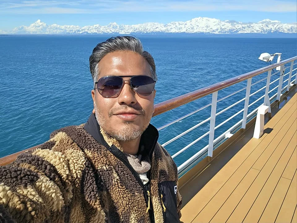 Cruising with Danny and Peter, Holland America Line, Westerdam, Hubbard Glacier, Alaska, United States | View of Hubbard Glacier from the boat during an unforgettable tour, showcasing stunning blue ice and calm Arctic waters. Thrilling ice calving event captures large chunks of ice breaking off and crashing into the water. Mirror-like reflection of the glacier on still waters highlights its majestic blue hues. A delightful picnic with the glacier in the background combines delicious food with breathtaking views, while a close-up of the glacier's intricate ice formations shows deep crevasses and jagged edges.