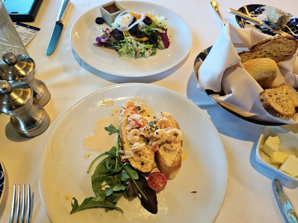 Cruising with Danny and Peter, Holland America Line, Westerdam, Hubbard Glacier, Alaska, United States | View of Hubbard Glacier from the boat during an unforgettable tour, showcasing stunning blue ice and calm Arctic waters. Thrilling ice calving event captures large chunks of ice breaking off and crashing into the water. Mirror-like reflection of the glacier on still waters highlights its majestic blue hues. A delightful picnic with the glacier in the background combines delicious food with breathtaking views, while a close-up of the glacier's intricate ice formations shows deep crevasses and jagged edges.