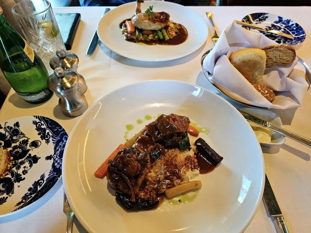 Cruising with Danny and Peter, Holland America Line, Westerdam, Hubbard Glacier, Alaska, United States | View of Hubbard Glacier from the boat during an unforgettable tour, showcasing stunning blue ice and calm Arctic waters. Thrilling ice calving event captures large chunks of ice breaking off and crashing into the water. Mirror-like reflection of the glacier on still waters highlights its majestic blue hues. A delightful picnic with the glacier in the background combines delicious food with breathtaking views, while a close-up of the glacier's intricate ice formations shows deep crevasses and jagged edges.
