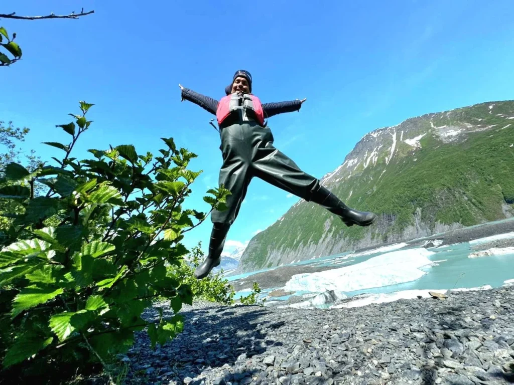 Cruising with Danny and Peter, Holland America Line, Westerdam, Prince William Sound, Valdez, Alaska, United States | A serene panorama of Prince William Sound at dawn, with the luxurious Westerdam cruise ship gliding through calm waters, surrounded by snow-capped mountains and glowing glaciers under a soft pink sky. Humpback whales breach the surface, their tails splashing against the reflective water, while sea otters float playfully in kelp beds and a bald eagle soars overhead. In Valdez Glacier Lake, vibrant blue icebergs drift peacefully, with kayakers in colorful kayaks paddling through the icy maze, dwarfed by the towering Valdez Glacier’s rugged ice face in the background. The Westerdam’s elegant deck features passengers enjoying a gourmet breakfast with panoramic views of the Alaskan wilderness, capturing the harmonious blend of luxury and nature.