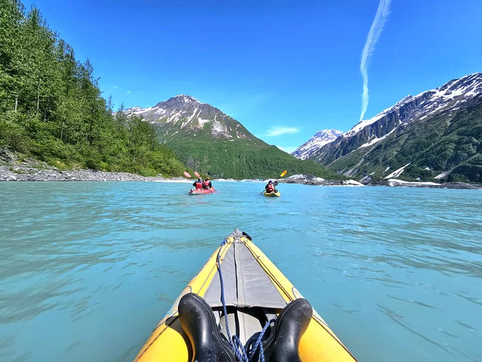 Cruising with Danny and Peter, Holland America Line, Westerdam, Prince William Sound, Valdez, Alaska, United States | A serene panorama of Prince William Sound at dawn, with the luxurious Westerdam cruise ship gliding through calm waters, surrounded by snow-capped mountains and glowing glaciers under a soft pink sky. Humpback whales breach the surface, their tails splashing against the reflective water, while sea otters float playfully in kelp beds and a bald eagle soars overhead. In Valdez Glacier Lake, vibrant blue icebergs drift peacefully, with kayakers in colorful kayaks paddling through the icy maze, dwarfed by the towering Valdez Glacier’s rugged ice face in the background. The Westerdam’s elegant deck features passengers enjoying a gourmet breakfast with panoramic views of the Alaskan wilderness, capturing the harmonious blend of luxury and nature.