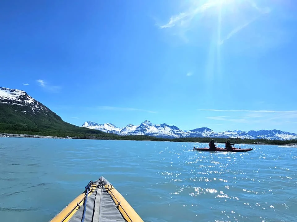 Cruising with Danny and Peter, Holland America Line, Westerdam, Prince William Sound, Valdez, Alaska, United States | A serene panorama of Prince William Sound at dawn, with the luxurious Westerdam cruise ship gliding through calm waters, surrounded by snow-capped mountains and glowing glaciers under a soft pink sky. Humpback whales breach the surface, their tails splashing against the reflective water, while sea otters float playfully in kelp beds and a bald eagle soars overhead. In Valdez Glacier Lake, vibrant blue icebergs drift peacefully, with kayakers in colorful kayaks paddling through the icy maze, dwarfed by the towering Valdez Glacier’s rugged ice face in the background. The Westerdam’s elegant deck features passengers enjoying a gourmet breakfast with panoramic views of the Alaskan wilderness, capturing the harmonious blend of luxury and nature.