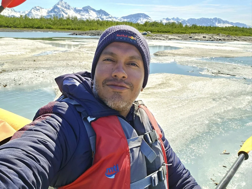 Cruising with Danny and Peter, Holland America Line, Westerdam, Prince William Sound, Valdez, Alaska, United States | A serene panorama of Prince William Sound at dawn, with the luxurious Westerdam cruise ship gliding through calm waters, surrounded by snow-capped mountains and glowing glaciers under a soft pink sky. Humpback whales breach the surface, their tails splashing against the reflective water, while sea otters float playfully in kelp beds and a bald eagle soars overhead. In Valdez Glacier Lake, vibrant blue icebergs drift peacefully, with kayakers in colorful kayaks paddling through the icy maze, dwarfed by the towering Valdez Glacier’s rugged ice face in the background. The Westerdam’s elegant deck features passengers enjoying a gourmet breakfast with panoramic views of the Alaskan wilderness, capturing the harmonious blend of luxury and nature.