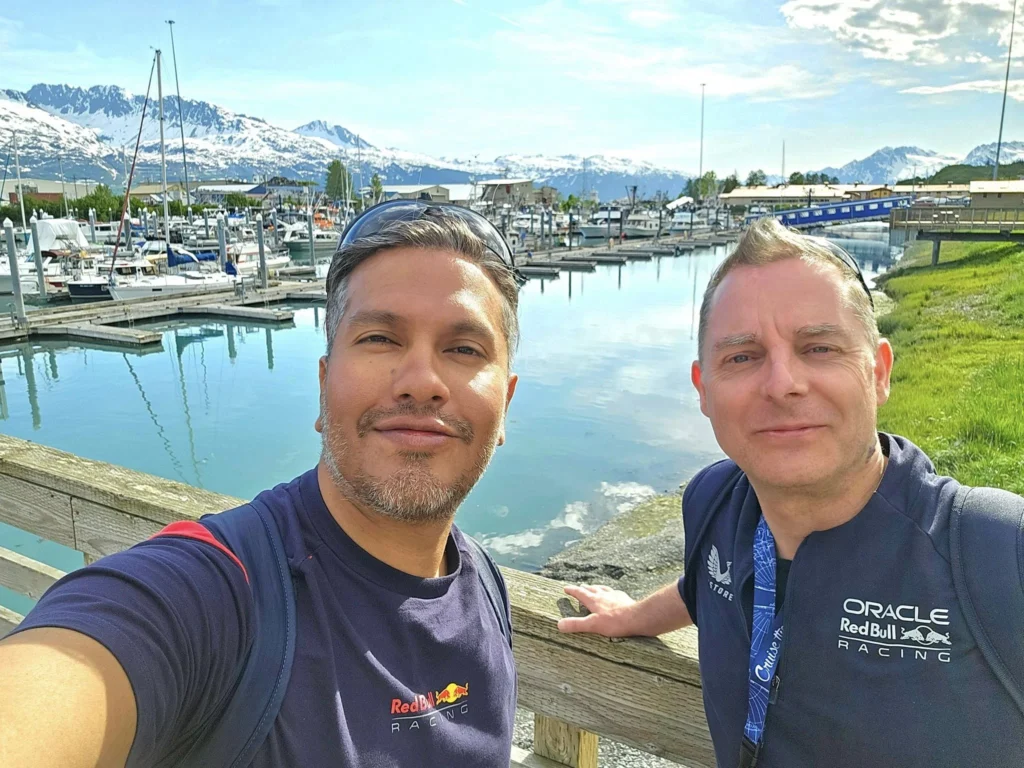 Cruising with Danny and Peter, Holland America Line, Westerdam, Prince William Sound, Valdez, Alaska, United States | A serene panorama of Prince William Sound at dawn, with the luxurious Westerdam cruise ship gliding through calm waters, surrounded by snow-capped mountains and glowing glaciers under a soft pink sky. Humpback whales breach the surface, their tails splashing against the reflective water, while sea otters float playfully in kelp beds and a bald eagle soars overhead. In Valdez Glacier Lake, vibrant blue icebergs drift peacefully, with kayakers in colorful kayaks paddling through the icy maze, dwarfed by the towering Valdez Glacier’s rugged ice face in the background. The Westerdam’s elegant deck features passengers enjoying a gourmet breakfast with panoramic views of the Alaskan wilderness, capturing the harmonious blend of luxury and nature.