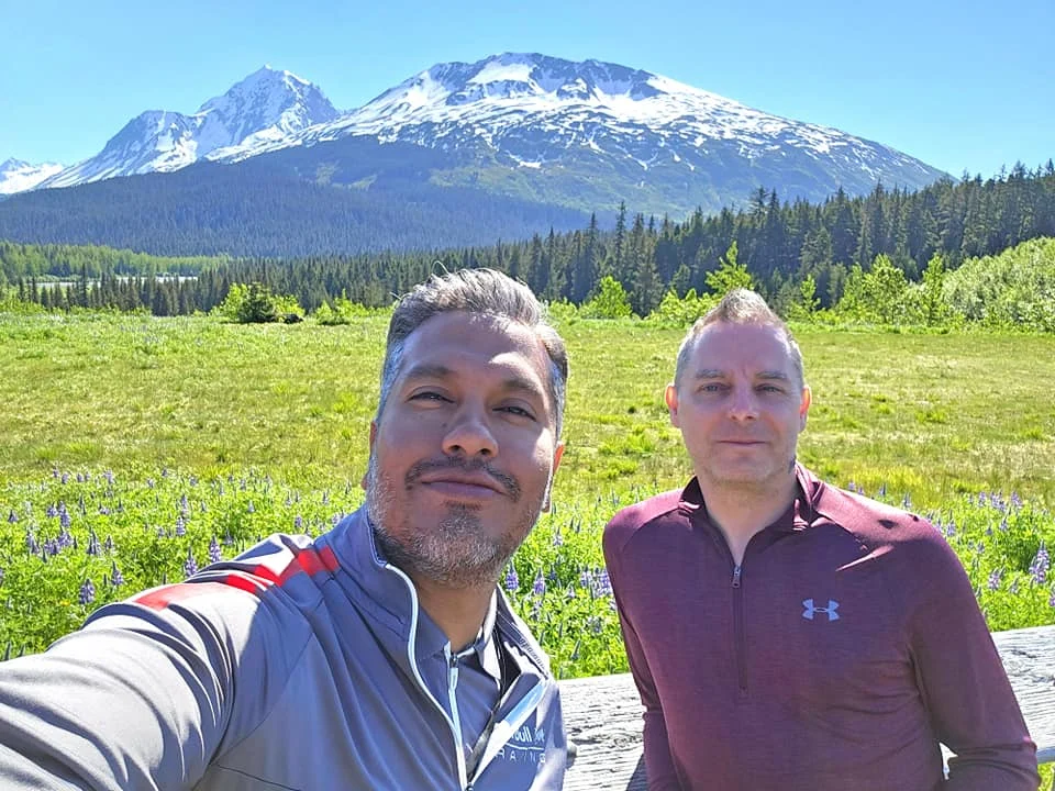 Cruising with Danny and Peter, Holland America Line, Westerdam, Seward, Alaska, United States | A panoramic view of Seward Harbor with rugged cliffs and serene waters, capturing Alaska's wilderness on a photography adventure. Travelers document vibrant wildflowers and snow-capped peaks in Chugach National Forest during an Alaska wilderness cruise. Historical remnants of the 1890 Gold Rush in Seward, including old mining equipment in lush alpine meadows, offer perfect scenes for photography enthusiasts. A majestic bald eagle soars over the tranquil waters of Seward Harbor, while senior-friendly guided tours explore accessible trails amidst stunning natural landscapes.