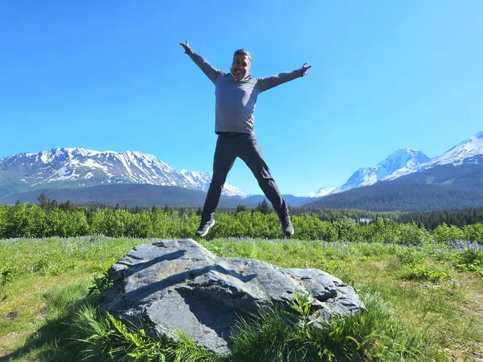 Cruising with Danny and Peter, Holland America Line, Westerdam, Seward, Alaska, United States | A panoramic view of Seward Harbor with rugged cliffs and serene waters, capturing Alaska's wilderness on a photography adventure. Travelers document vibrant wildflowers and snow-capped peaks in Chugach National Forest during an Alaska wilderness cruise. Historical remnants of the 1890 Gold Rush in Seward, including old mining equipment in lush alpine meadows, offer perfect scenes for photography enthusiasts. A majestic bald eagle soars over the tranquil waters of Seward Harbor, while senior-friendly guided tours explore accessible trails amidst stunning natural landscapes.