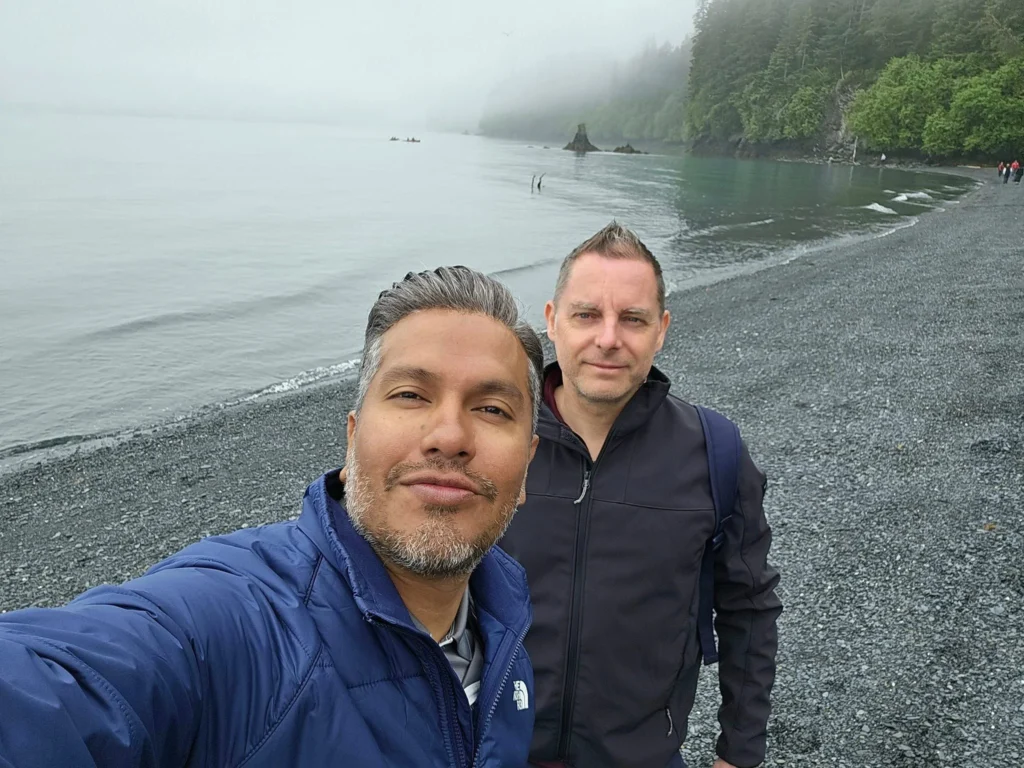 Cruising with Danny and Peter, Holland America Line, Westerdam, Seward, Alaska, United States | A panoramic view of Seward Harbor with rugged cliffs and serene waters, capturing Alaska's wilderness on a photography adventure. Travelers document vibrant wildflowers and snow-capped peaks in Chugach National Forest during an Alaska wilderness cruise. Historical remnants of the 1890 Gold Rush in Seward, including old mining equipment in lush alpine meadows, offer perfect scenes for photography enthusiasts. A majestic bald eagle soars over the tranquil waters of Seward Harbor, while senior-friendly guided tours explore accessible trails amidst stunning natural landscapes.