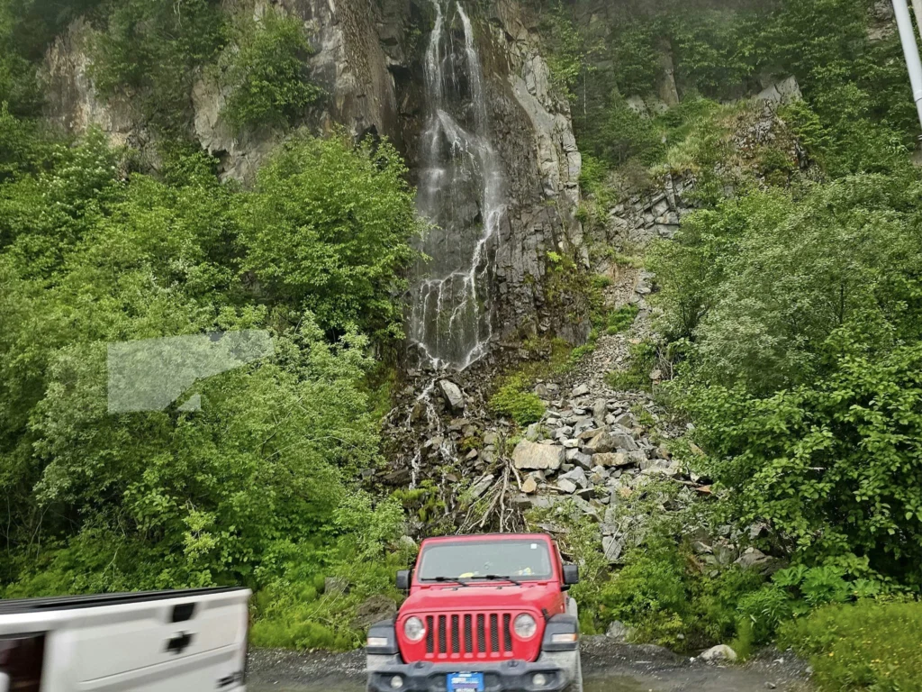Cruising with Danny and Peter, Holland America Line, Westerdam, Seward, Alaska, United States | A panoramic view of Seward Harbor with rugged cliffs and serene waters, capturing Alaska's wilderness on a photography adventure. Travelers document vibrant wildflowers and snow-capped peaks in Chugach National Forest during an Alaska wilderness cruise. Historical remnants of the 1890 Gold Rush in Seward, including old mining equipment in lush alpine meadows, offer perfect scenes for photography enthusiasts. A majestic bald eagle soars over the tranquil waters of Seward Harbor, while senior-friendly guided tours explore accessible trails amidst stunning natural landscapes.