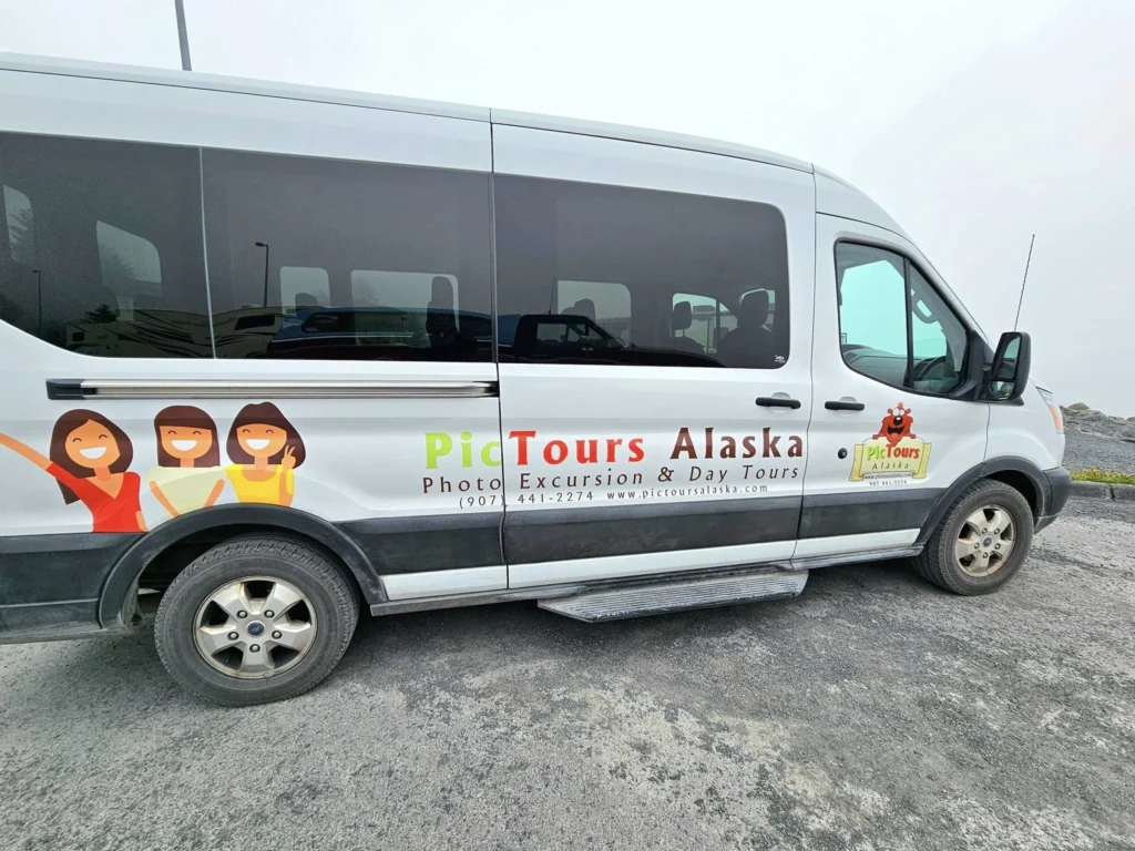 Cruising with Danny and Peter, Holland America Line, Westerdam, Seward, Alaska, United States | A panoramic view of Seward Harbor with rugged cliffs and serene waters, capturing Alaska's wilderness on a photography adventure. Travelers document vibrant wildflowers and snow-capped peaks in Chugach National Forest during an Alaska wilderness cruise. Historical remnants of the 1890 Gold Rush in Seward, including old mining equipment in lush alpine meadows, offer perfect scenes for photography enthusiasts. A majestic bald eagle soars over the tranquil waters of Seward Harbor, while senior-friendly guided tours explore accessible trails amidst stunning natural landscapes.