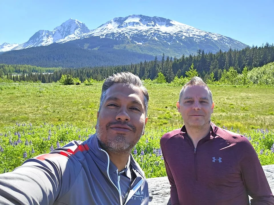 Cruising with Danny and Peter, Holland America Line, Westerdam, Seward, Alaska, United States | A panoramic view of Seward Harbor with rugged cliffs and serene waters, capturing Alaska's wilderness on a photography adventure. Travelers document vibrant wildflowers and snow-capped peaks in Chugach National Forest during an Alaska wilderness cruise. Historical remnants of the 1890 Gold Rush in Seward, including old mining equipment in lush alpine meadows, offer perfect scenes for photography enthusiasts. A majestic bald eagle soars over the tranquil waters of Seward Harbor, while senior-friendly guided tours explore accessible trails amidst stunning natural landscapes.