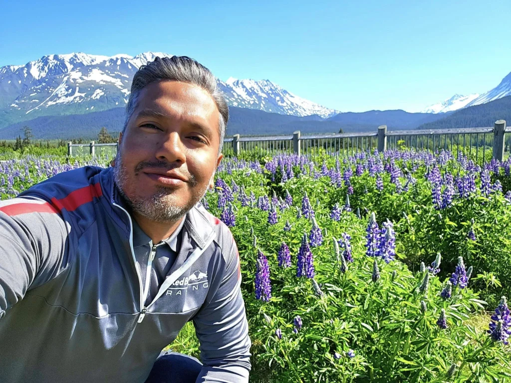 Cruising with Danny and Peter, Holland America Line, Westerdam, Seward, Alaska, United States | A panoramic view of Seward Harbor with rugged cliffs and serene waters, capturing Alaska's wilderness on a photography adventure. Travelers document vibrant wildflowers and snow-capped peaks in Chugach National Forest during an Alaska wilderness cruise. Historical remnants of the 1890 Gold Rush in Seward, including old mining equipment in lush alpine meadows, offer perfect scenes for photography enthusiasts. A majestic bald eagle soars over the tranquil waters of Seward Harbor, while senior-friendly guided tours explore accessible trails amidst stunning natural landscapes.
