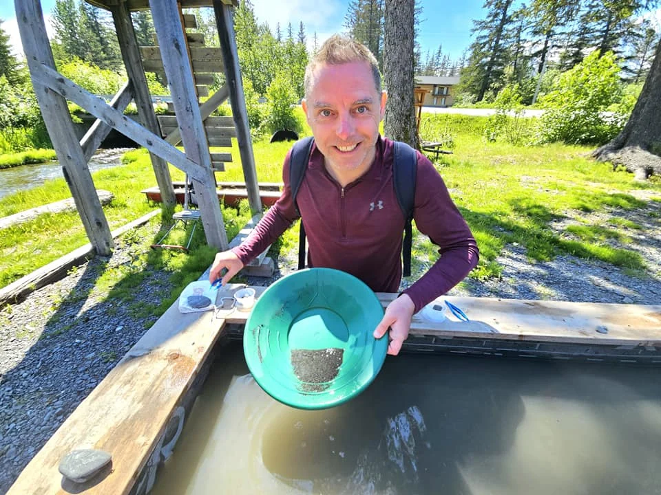 Cruising with Danny and Peter, Holland America Line, Westerdam, Seward, Alaska, United States | A panoramic view of Seward Harbor with rugged cliffs and serene waters, capturing Alaska's wilderness on a photography adventure. Travelers document vibrant wildflowers and snow-capped peaks in Chugach National Forest during an Alaska wilderness cruise. Historical remnants of the 1890 Gold Rush in Seward, including old mining equipment in lush alpine meadows, offer perfect scenes for photography enthusiasts. A majestic bald eagle soars over the tranquil waters of Seward Harbor, while senior-friendly guided tours explore accessible trails amidst stunning natural landscapes.
