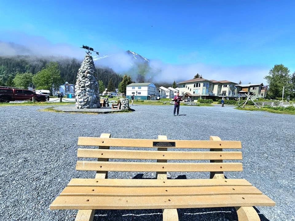 Cruising with Danny and Peter, Holland America Line, Westerdam, Seward, Alaska, United States | A panoramic view of Seward Harbor with rugged cliffs and serene waters, capturing Alaska's wilderness on a photography adventure. Travelers document vibrant wildflowers and snow-capped peaks in Chugach National Forest during an Alaska wilderness cruise. Historical remnants of the 1890 Gold Rush in Seward, including old mining equipment in lush alpine meadows, offer perfect scenes for photography enthusiasts. A majestic bald eagle soars over the tranquil waters of Seward Harbor, while senior-friendly guided tours explore accessible trails amidst stunning natural landscapes.