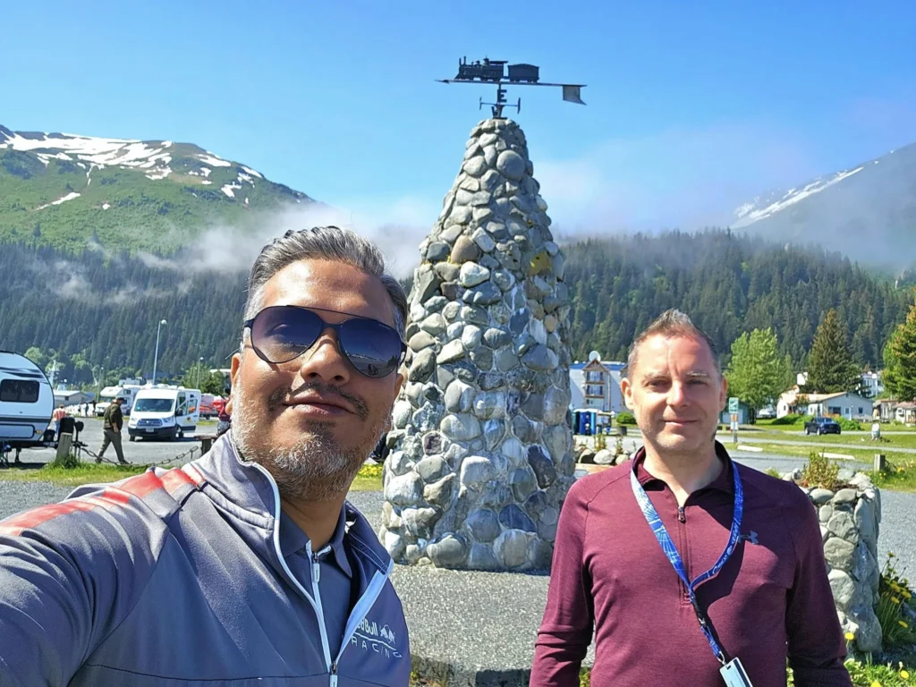 Cruising with Danny and Peter, Holland America Line, Westerdam, Seward, Alaska, United States | A panoramic view of Seward Harbor with rugged cliffs and serene waters, capturing Alaska's wilderness on a photography adventure. Travelers document vibrant wildflowers and snow-capped peaks in Chugach National Forest during an Alaska wilderness cruise. Historical remnants of the 1890 Gold Rush in Seward, including old mining equipment in lush alpine meadows, offer perfect scenes for photography enthusiasts. A majestic bald eagle soars over the tranquil waters of Seward Harbor, while senior-friendly guided tours explore accessible trails amidst stunning natural landscapes.