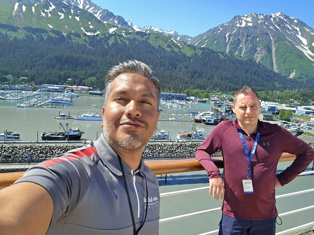 Cruising with Danny and Peter, Holland America Line, Westerdam, Seward, Alaska, United States | A panoramic view of Seward Harbor with rugged cliffs and serene waters, capturing Alaska's wilderness on a photography adventure. Travelers document vibrant wildflowers and snow-capped peaks in Chugach National Forest during an Alaska wilderness cruise. Historical remnants of the 1890 Gold Rush in Seward, including old mining equipment in lush alpine meadows, offer perfect scenes for photography enthusiasts. A majestic bald eagle soars over the tranquil waters of Seward Harbor, while senior-friendly guided tours explore accessible trails amidst stunning natural landscapes.