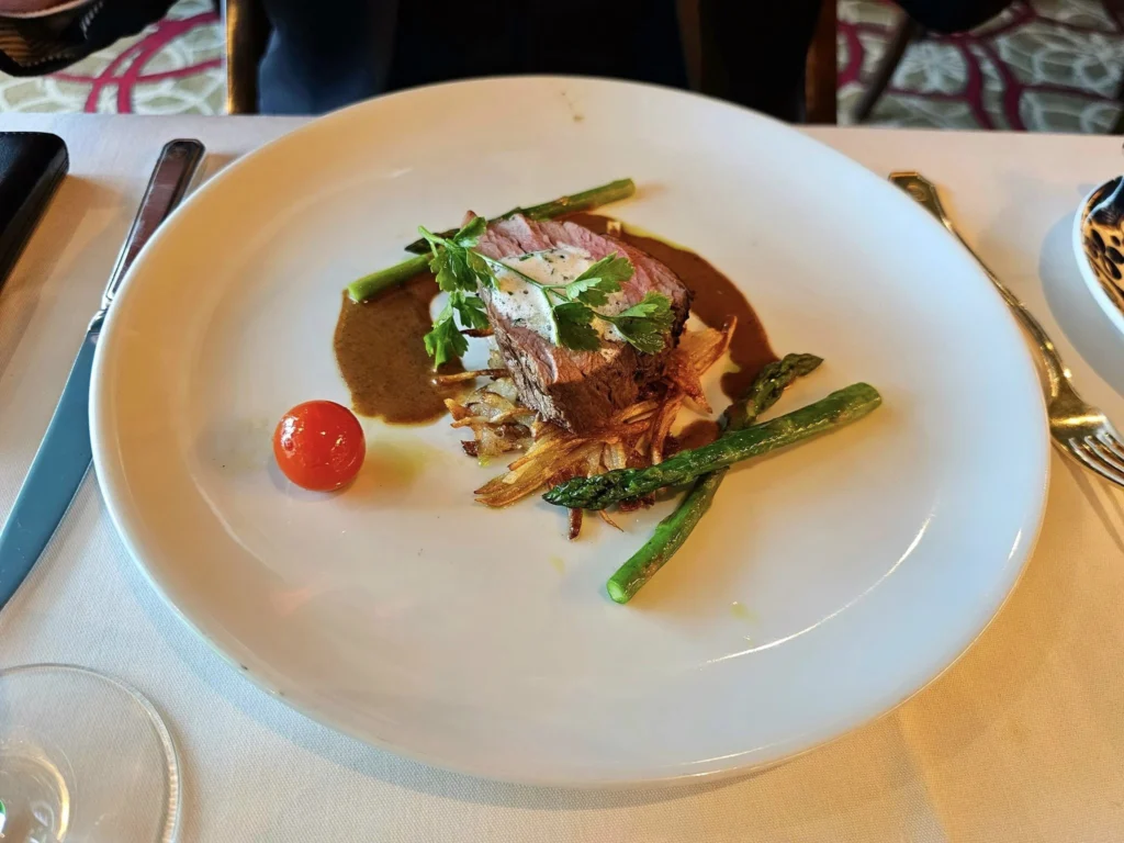 Cruising with Danny and Peter, Holland America Line, Westerdam, Seward, Alaska, United States | A panoramic view of Seward Harbor with rugged cliffs and serene waters, capturing Alaska's wilderness on a photography adventure. Travelers document vibrant wildflowers and snow-capped peaks in Chugach National Forest during an Alaska wilderness cruise. Historical remnants of the 1890 Gold Rush in Seward, including old mining equipment in lush alpine meadows, offer perfect scenes for photography enthusiasts. A majestic bald eagle soars over the tranquil waters of Seward Harbor, while senior-friendly guided tours explore accessible trails amidst stunning natural landscapes.