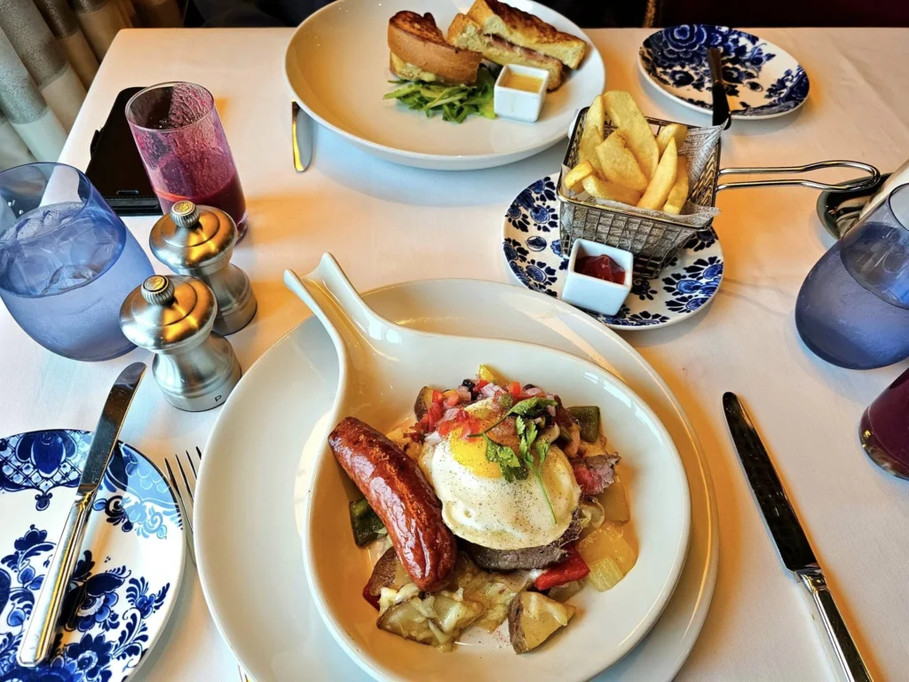 Cruising with Danny and Peter, Holland America Line, Westerdam, Gulf of Alaska, Alaska, United States | Elegant dining room with panoramic ocean views during an Alaska sea day brunch, featuring a spread of gourmet dishes and Alaskan specialties.