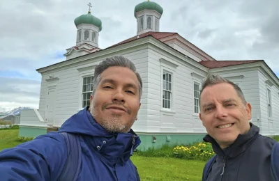 Cruising with Danny and Peter, Holland America Line, Westerdam, Dutch Harbor, Unlaska, Alaska, United States | Scenic view of Dutch Harbor Unalaska featuring rugged mountains and the Bering Sea, with a hiker on Mount Ballyhoo Trail, a majestic bald eagle soaring above, and the historic Russian Orthodox Church with its distinctive onion domes. Includes a fresh seafood dish representing local cuisine and a birdwatching spot at Unalaska Island Bird Sanctuary, capturing the charm of Unalaska's blend of natural beauty, wildlife, and cultural heritage.