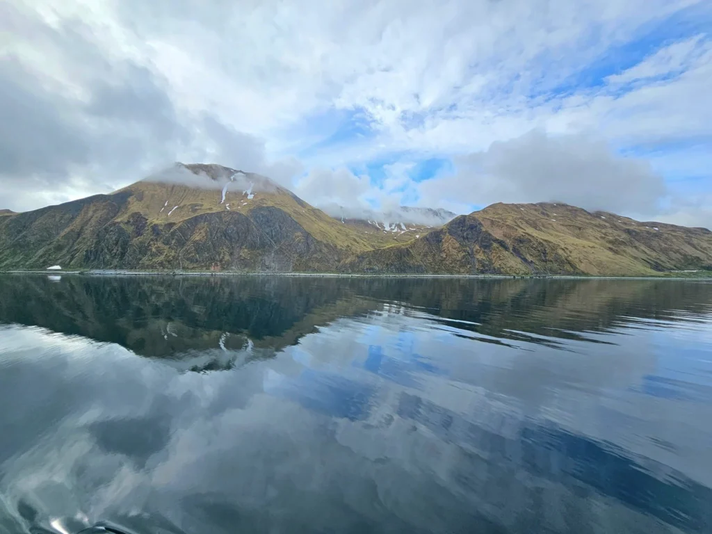 Cruising with Danny and Peter, Holland America Line, Westerdam, Dutch Harbor, Unlaska, Alaska, United States | Scenic view of Dutch Harbor Unalaska featuring rugged mountains and the Bering Sea, with a hiker on Mount Ballyhoo Trail, a majestic bald eagle soaring above, and the historic Russian Orthodox Church with its distinctive onion domes. Includes a fresh seafood dish representing local cuisine and a birdwatching spot at Unalaska Island Bird Sanctuary, capturing the charm of Unalaska's blend of natural beauty, wildlife, and cultural heritage.