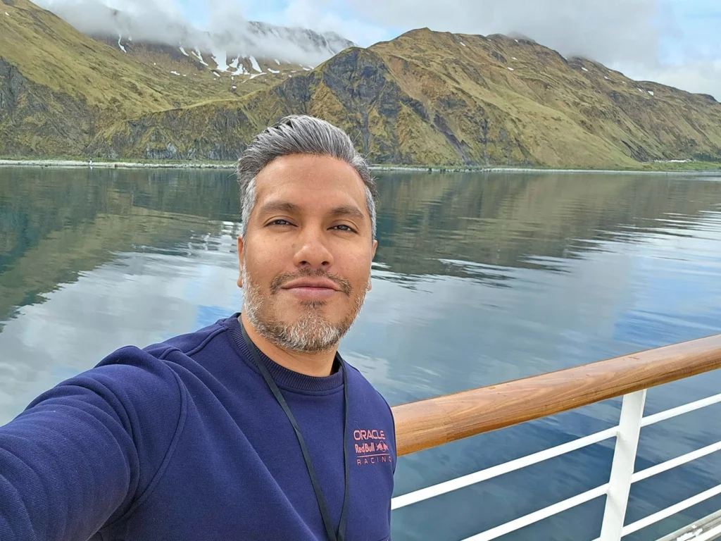 Cruising with Danny and Peter, Holland America Line, Westerdam, Dutch Harbor, Unlaska, Alaska, United States | Scenic view of Dutch Harbor Unalaska featuring rugged mountains and the Bering Sea, with a hiker on Mount Ballyhoo Trail, a majestic bald eagle soaring above, and the historic Russian Orthodox Church with its distinctive onion domes. Includes a fresh seafood dish representing local cuisine and a birdwatching spot at Unalaska Island Bird Sanctuary, capturing the charm of Unalaska's blend of natural beauty, wildlife, and cultural heritage.