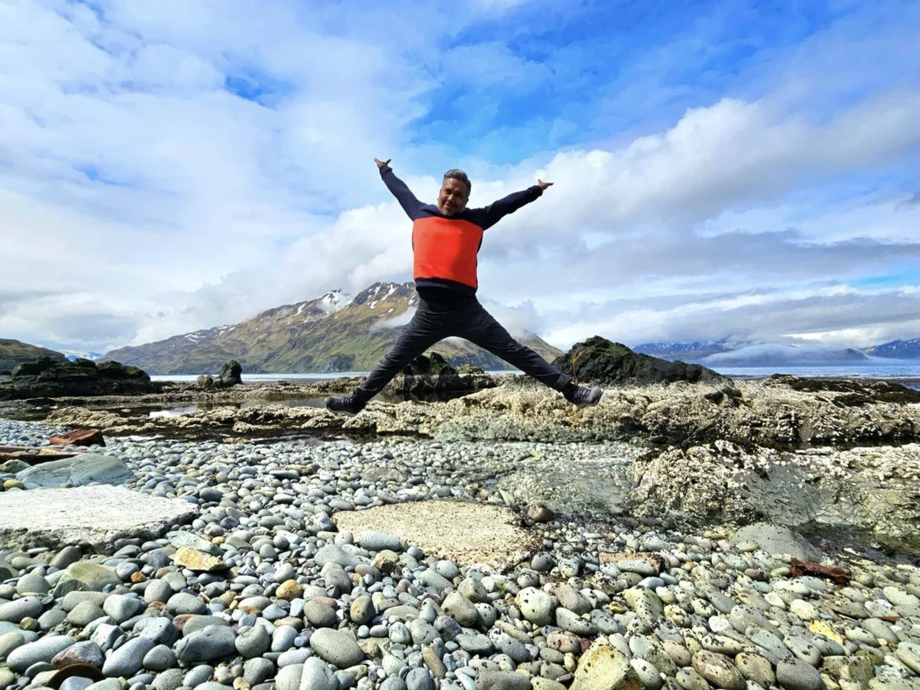 Cruising with Danny and Peter, Holland America Line, Westerdam, Dutch Harbor, Unlaska, Alaska, United States | Scenic view of Dutch Harbor Unalaska featuring rugged mountains and the Bering Sea, with a hiker on Mount Ballyhoo Trail, a majestic bald eagle soaring above, and the historic Russian Orthodox Church with its distinctive onion domes. Includes a fresh seafood dish representing local cuisine and a birdwatching spot at Unalaska Island Bird Sanctuary, capturing the charm of Unalaska's blend of natural beauty, wildlife, and cultural heritage.