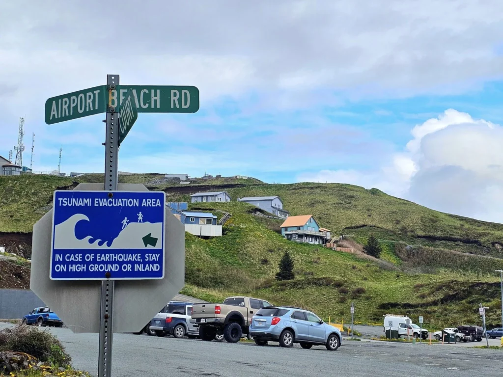 Cruising with Danny and Peter, Holland America Line, Westerdam, Dutch Harbor, Unlaska, Alaska, United States | Scenic view of Dutch Harbor Unalaska featuring rugged mountains and the Bering Sea, with a hiker on Mount Ballyhoo Trail, a majestic bald eagle soaring above, and the historic Russian Orthodox Church with its distinctive onion domes. Includes a fresh seafood dish representing local cuisine and a birdwatching spot at Unalaska Island Bird Sanctuary, capturing the charm of Unalaska's blend of natural beauty, wildlife, and cultural heritage.