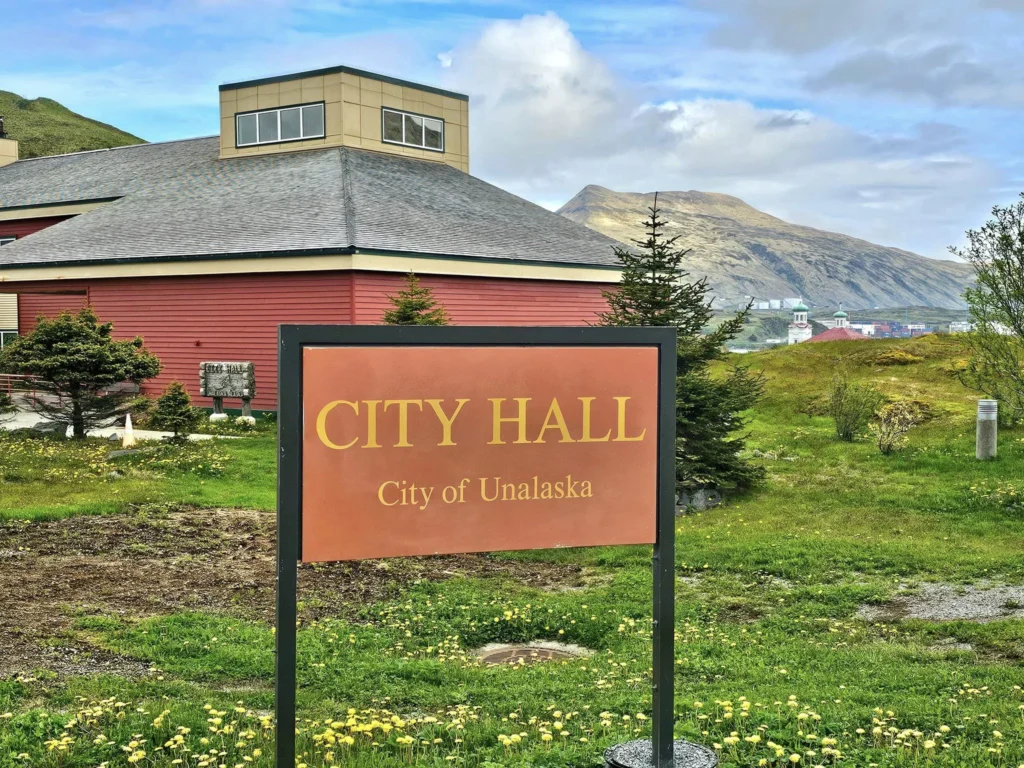 Cruising with Danny and Peter, Holland America Line, Westerdam, Dutch Harbor, Unlaska, Alaska, United States | Scenic view of Dutch Harbor Unalaska featuring rugged mountains and the Bering Sea, with a hiker on Mount Ballyhoo Trail, a majestic bald eagle soaring above, and the historic Russian Orthodox Church with its distinctive onion domes. Includes a fresh seafood dish representing local cuisine and a birdwatching spot at Unalaska Island Bird Sanctuary, capturing the charm of Unalaska's blend of natural beauty, wildlife, and cultural heritage.