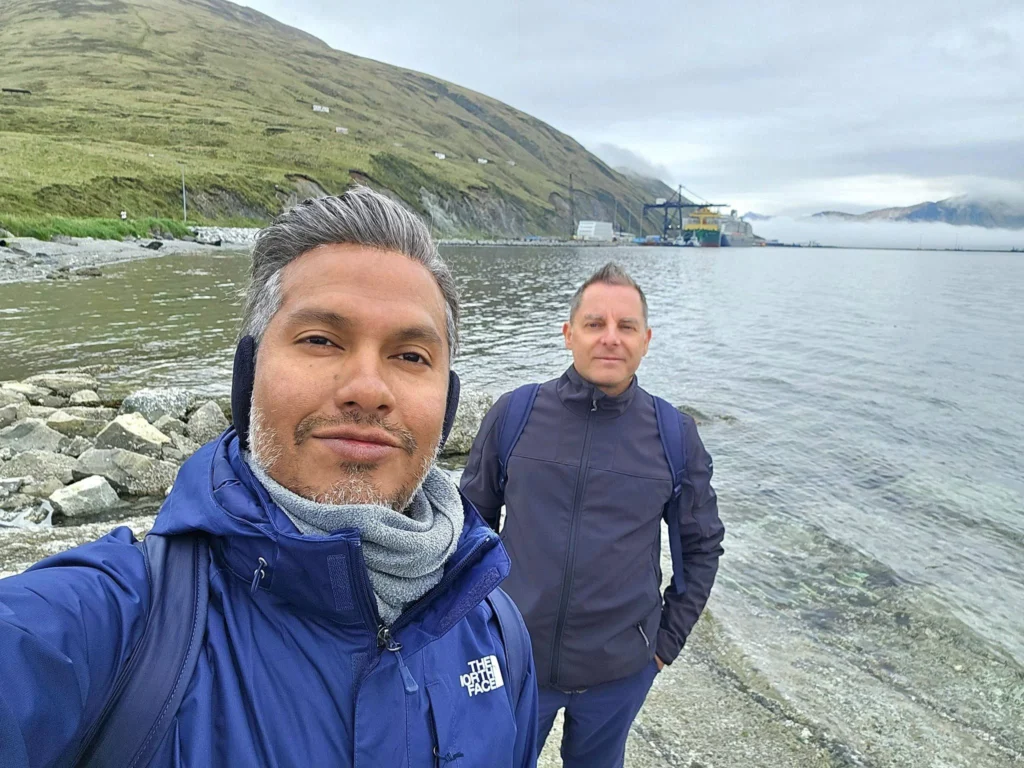 Cruising with Danny and Peter, Holland America Line, Westerdam, Dutch Harbor, Unlaska, Alaska, United States | Scenic view of Dutch Harbor Unalaska featuring rugged mountains and the Bering Sea, with a hiker on Mount Ballyhoo Trail, a majestic bald eagle soaring above, and the historic Russian Orthodox Church with its distinctive onion domes. Includes a fresh seafood dish representing local cuisine and a birdwatching spot at Unalaska Island Bird Sanctuary, capturing the charm of Unalaska's blend of natural beauty, wildlife, and cultural heritage.