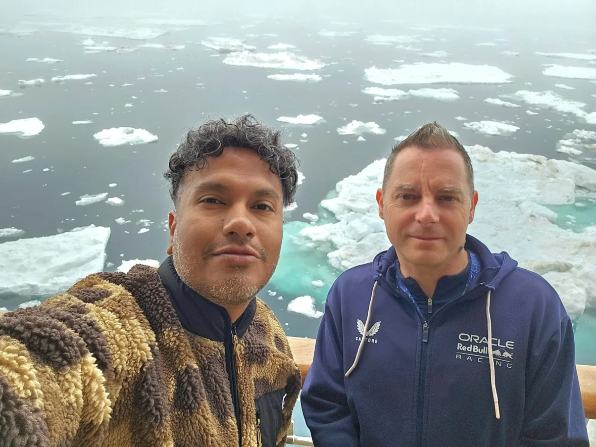 Cruising with Danny and Peter, Holland America Line, Westerdam, Bering Sea, Alaska, United States, Arctic Circle Adventure | A vibrant scene aboard Holland America Line’s Westerdam during the Alaska Arctic Circle Solstice cruise in the Bering Sea, Alaska, United States. Passengers gather around the Lido pool, preparing for the exhilarating Polar Bear Plunge, with crew members setting up the chilled pool to simulate Arctic waters. In the background, stunning Arctic landscapes unfold, featuring pristine ice floes floating on deep blue waters under a golden-hued sky, with distant glaciers and occasional wildlife, such as seals and seabirds, enhancing the untamed beauty of the Frozen Sea Adventure.