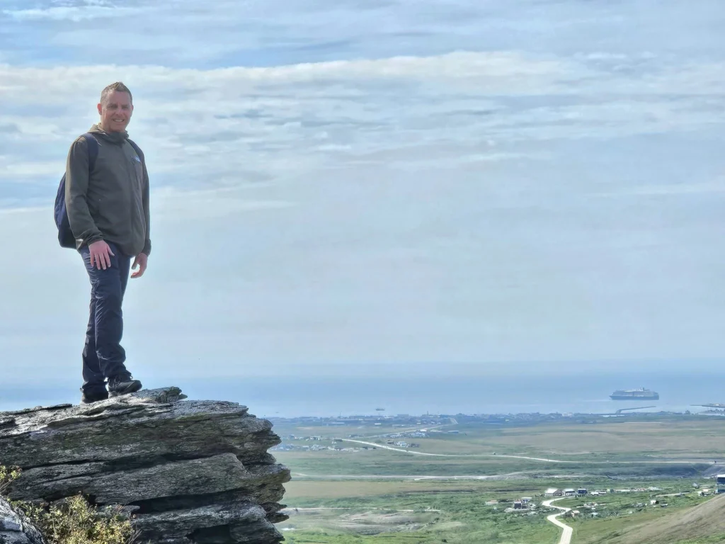 Discovering Newton Peak Hike in Nome, Alaska: A Comprehensive Adventure Guide 53 Cruising with Danny and Peter, Holland America Line, Westerdam, Nome, Alaska, United States | Scenic images of the Newton Peak Hike in Nome, Alaska, including the trailhead marking the start of the adventure, hikers ascending the challenging terrain, panoramic summit views of rolling hills and the Bering Sea, wildlife like curious squirrels and soaring birds along the trail, and vibrant wildflowers adding color to the rugged landscape.