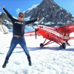 Cruising with Danny and Peter, Holland America Line, Westerdam, Anchorage, Alaska, United States | Aerial view of Denali, North America's tallest peak, and the majestic Alaska Range, captured during a Denali National Park flightseeing tour from Anchorage. The image also shows the stunning Ruth Glacier, a specialized plane with skis landing on Denali's snowy terrain, and wildlife such as moose grazing and beluga whales swimming in Cook Inlet.