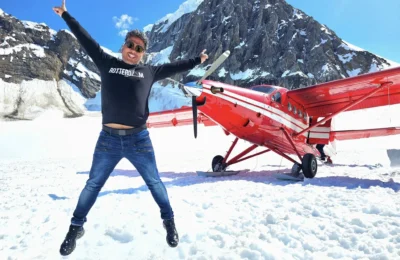 Cruising with Danny and Peter, Holland America Line, Westerdam, Anchorage, Alaska, United States | Aerial view of Denali, North America's tallest peak, and the majestic Alaska Range, captured during a Denali National Park flightseeing tour from Anchorage. The image also shows the stunning Ruth Glacier, a specialized plane with skis landing on Denali's snowy terrain, and wildlife such as moose grazing and beluga whales swimming in Cook Inlet.