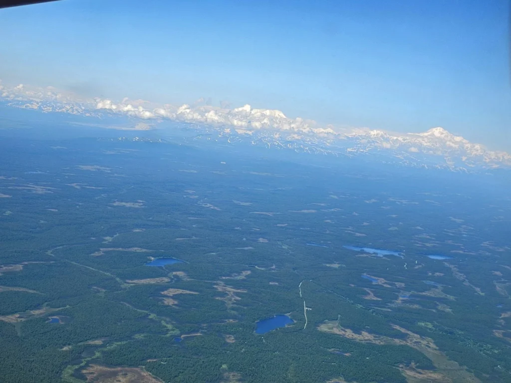 Unforgettable Alaska Flightseeing: A Journey Over Denali National Park 28 Cruising with Danny and Peter, Holland America Line, Westerdam, Anchorage, Alaska, United States | Aerial view of Denali, North America's tallest peak, and the majestic Alaska Range, captured during a Denali National Park flightseeing tour from Anchorage. The image also shows the stunning Ruth Glacier, a specialized plane with skis landing on Denali's snowy terrain, and wildlife such as moose grazing and beluga whales swimming in Cook Inlet.