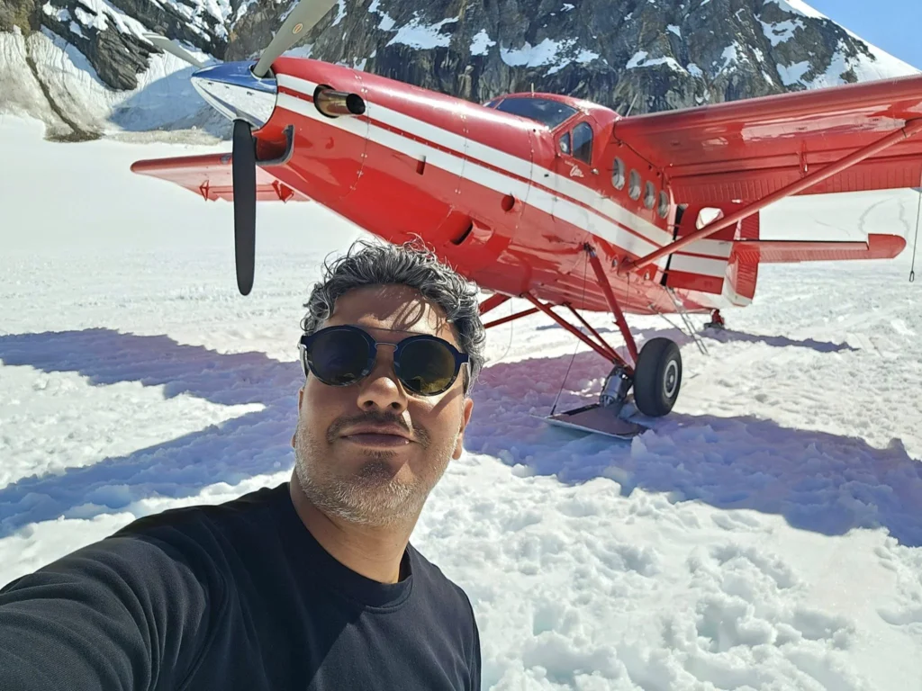 Unforgettable Alaska Flightseeing: A Journey Over Denali National Park 63 Cruising with Danny and Peter, Holland America Line, Westerdam, Anchorage, Alaska, United States | Aerial view of Denali, North America's tallest peak, and the majestic Alaska Range, captured during a Denali National Park flightseeing tour from Anchorage. The image also shows the stunning Ruth Glacier, a specialized plane with skis landing on Denali's snowy terrain, and wildlife such as moose grazing and beluga whales swimming in Cook Inlet.