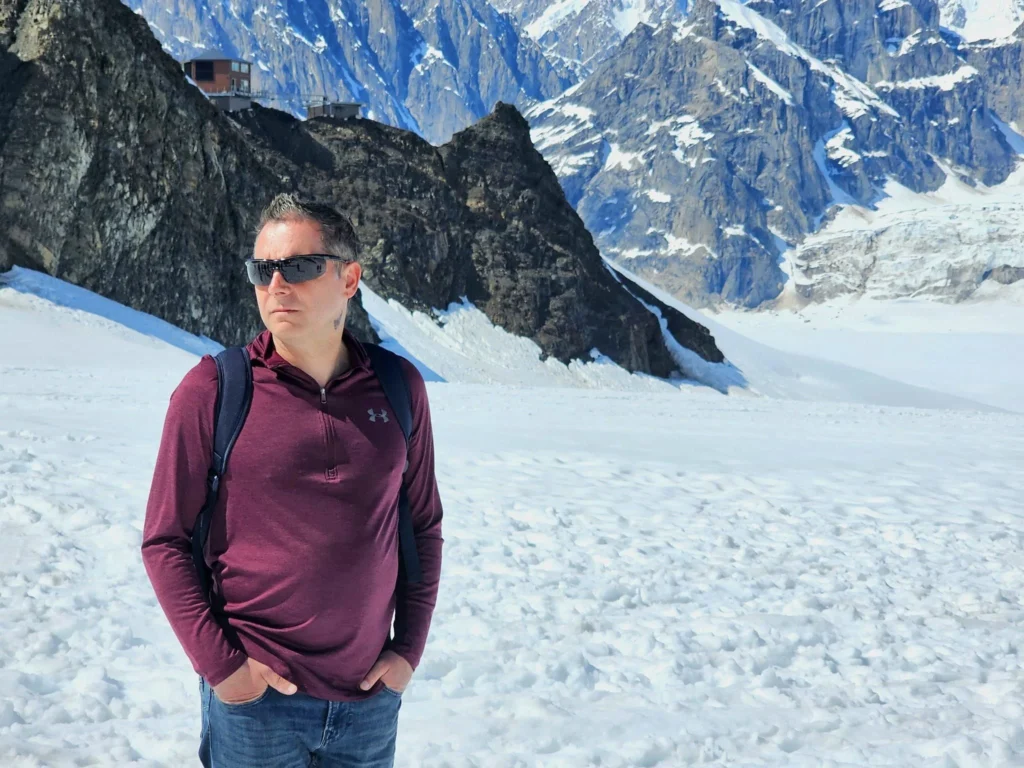 Unforgettable Alaska Flightseeing: A Journey Over Denali National Park 66 Cruising with Danny and Peter, Holland America Line, Westerdam, Anchorage, Alaska, United States | Aerial view of Denali, North America's tallest peak, and the majestic Alaska Range, captured during a Denali National Park flightseeing tour from Anchorage. The image also shows the stunning Ruth Glacier, a specialized plane with skis landing on Denali's snowy terrain, and wildlife such as moose grazing and beluga whales swimming in Cook Inlet.