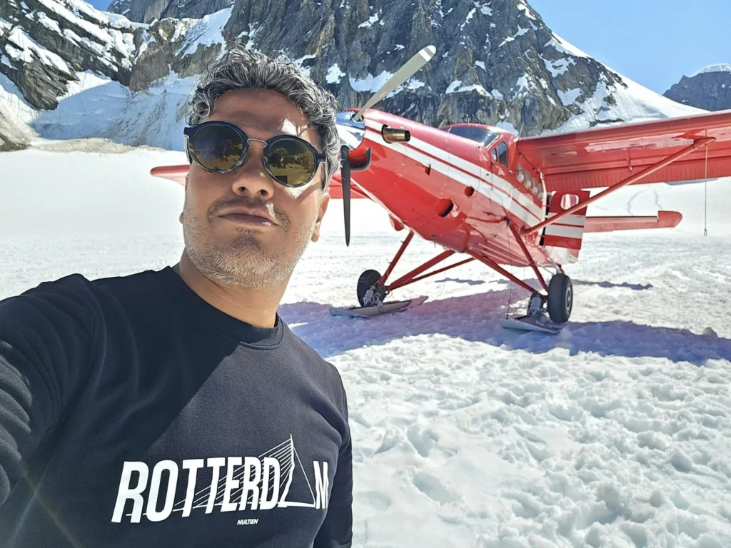 Unforgettable Alaska Flightseeing: A Journey Over Denali National Park 68 Cruising with Danny and Peter, Holland America Line, Westerdam, Anchorage, Alaska, United States | Aerial view of Denali, North America's tallest peak, and the majestic Alaska Range, captured during a Denali National Park flightseeing tour from Anchorage. The image also shows the stunning Ruth Glacier, a specialized plane with skis landing on Denali's snowy terrain, and wildlife such as moose grazing and beluga whales swimming in Cook Inlet.
