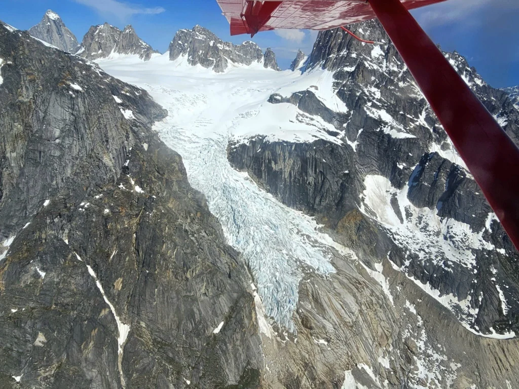 Unforgettable Alaska Flightseeing: A Journey Over Denali National Park 12 Cruising with Danny and Peter, Holland America Line, Westerdam, Anchorage, Alaska, United States | Aerial view of Denali, North America's tallest peak, and the majestic Alaska Range, captured during a Denali National Park flightseeing tour from Anchorage. The image also shows the stunning Ruth Glacier, a specialized plane with skis landing on Denali's snowy terrain, and wildlife such as moose grazing and beluga whales swimming in Cook Inlet.