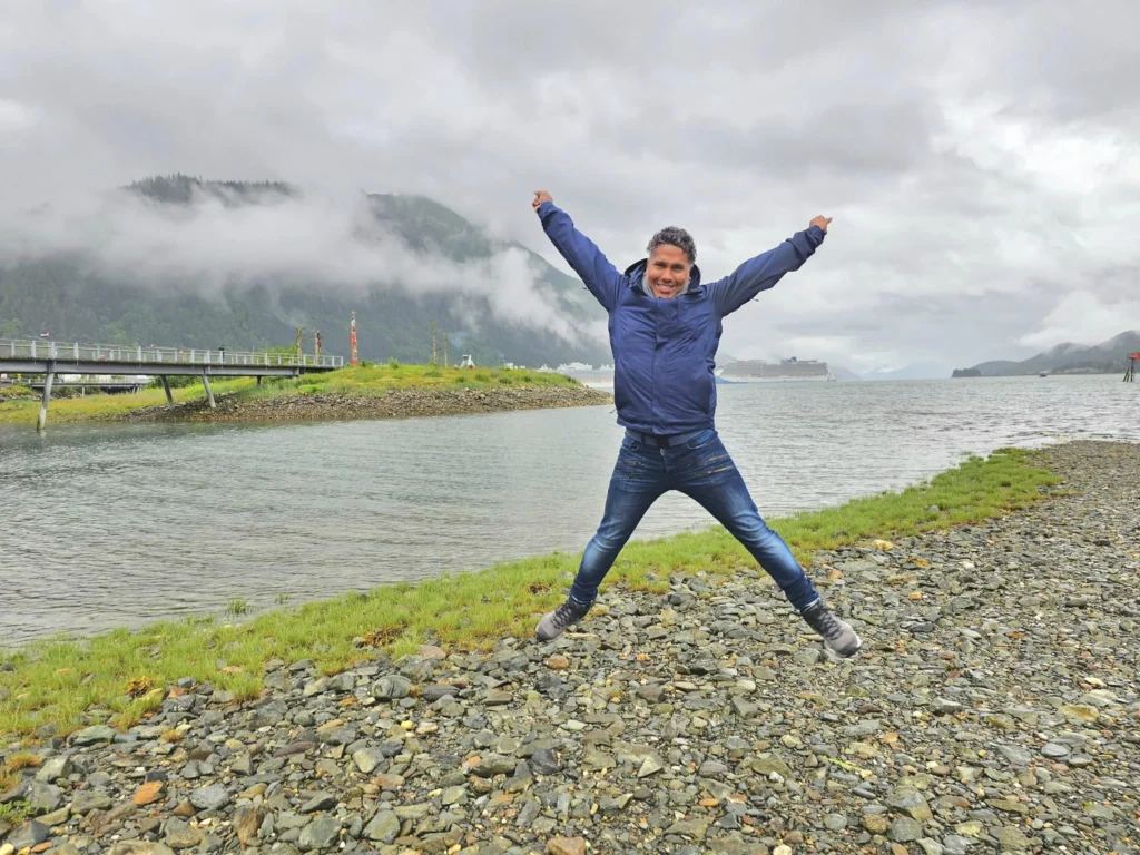 Cruising with Danny and Peter, Holland America Line, Westerdam, Juneau, Alaska, United States | Boat approaching Sentinel Island Lighthouse during Alaska whale watching tour, with humpback whale and stunning coastal scenery in the background.