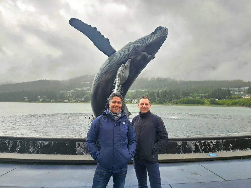 Cruising with Danny and Peter, Holland America Line, Westerdam, Juneau, Alaska, United States | Boat approaching Sentinel Island Lighthouse during Alaska whale watching tour, with humpback whale and stunning coastal scenery in the background.