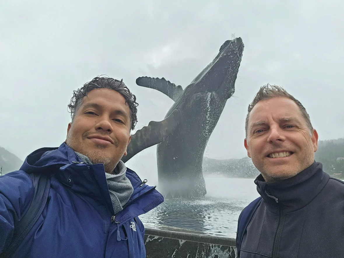 Cruising with Danny and Peter, Holland America Line, Westerdam, Juneau, Alaska, United States | Boat approaching Sentinel Island Lighthouse during Alaska whale watching tour, with humpback whale and stunning coastal scenery in the background.