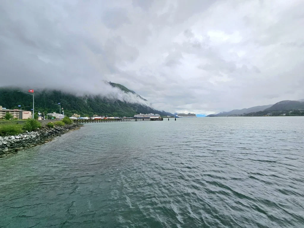 Cruising with Danny and Peter, Holland America Line, Westerdam, Juneau, Alaska, United States | Boat approaching Sentinel Island Lighthouse during Alaska whale watching tour, with humpback whale and stunning coastal scenery in the background.