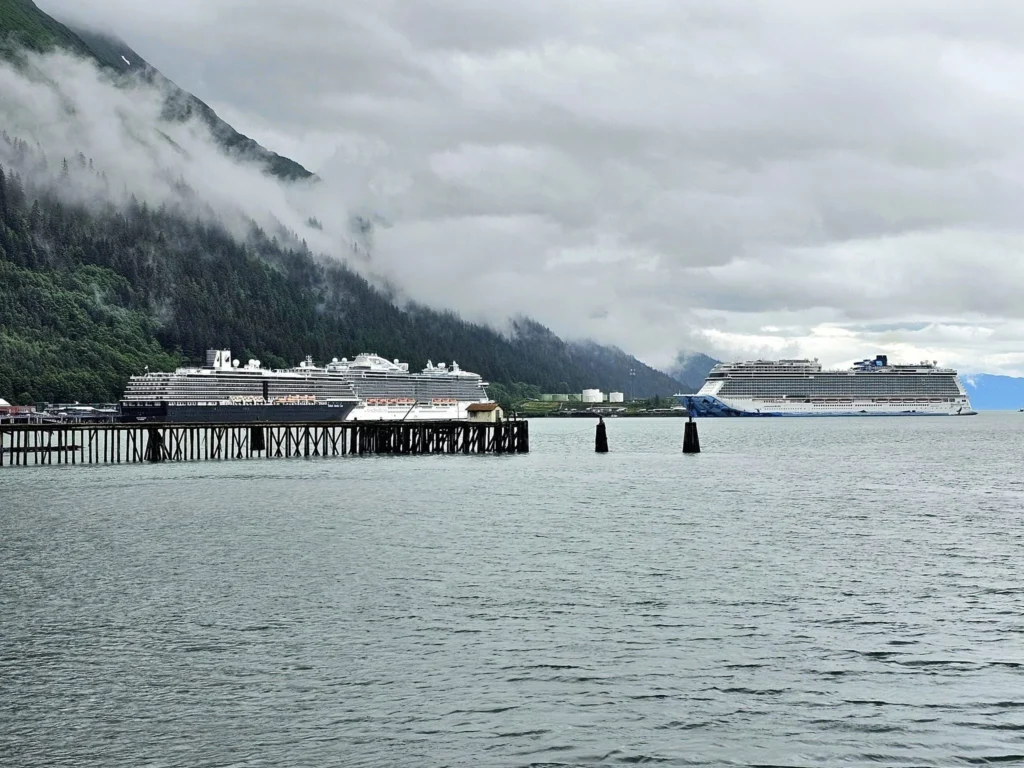 Cruising with Danny and Peter, Holland America Line, Westerdam, Juneau, Alaska, United States | Boat approaching Sentinel Island Lighthouse during Alaska whale watching tour, with humpback whale and stunning coastal scenery in the background.