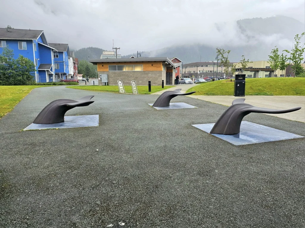 Cruising with Danny and Peter, Holland America Line, Westerdam, Juneau, Alaska, United States | Boat approaching Sentinel Island Lighthouse during Alaska whale watching tour, with humpback whale and stunning coastal scenery in the background.