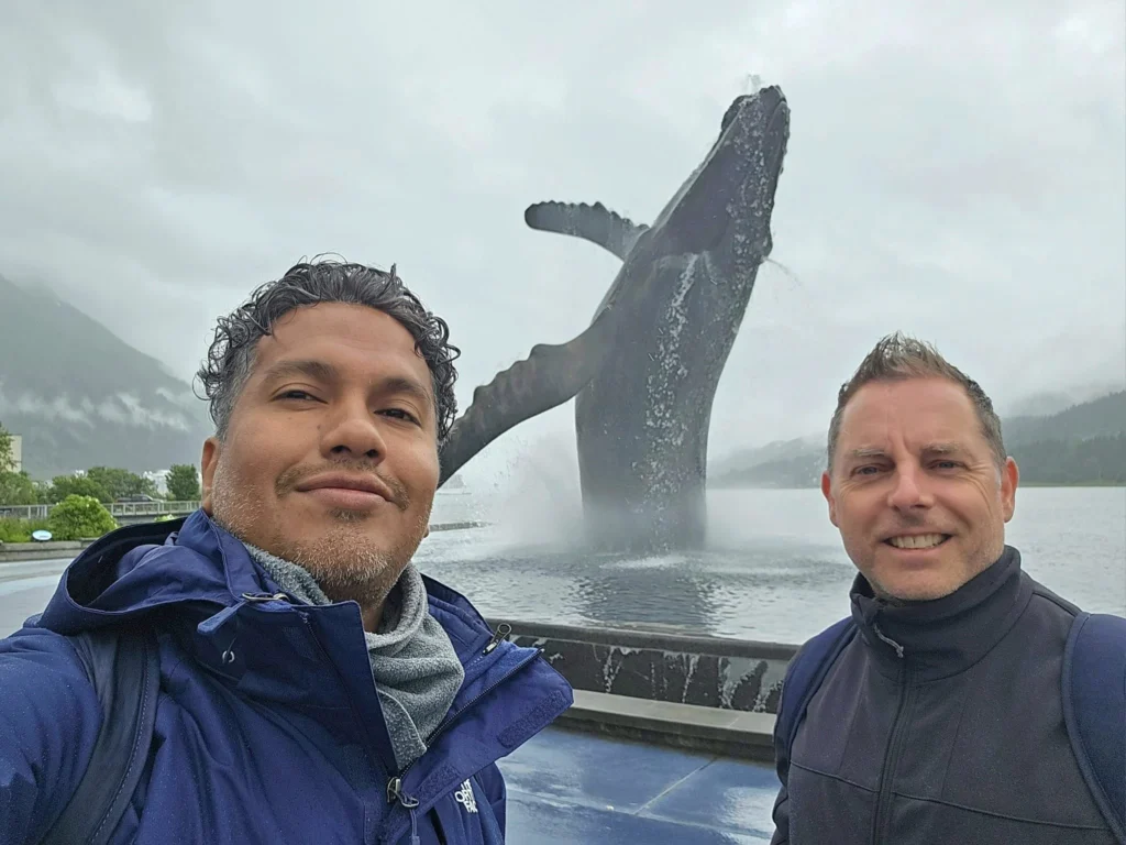 Cruising with Danny and Peter, Holland America Line, Westerdam, Juneau, Alaska, United States | Boat approaching Sentinel Island Lighthouse during Alaska whale watching tour, with humpback whale and stunning coastal scenery in the background.