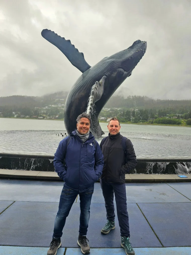 Cruising with Danny and Peter, Holland America Line, Westerdam, Juneau, Alaska, United States | Boat approaching Sentinel Island Lighthouse during Alaska whale watching tour, with humpback whale and stunning coastal scenery in the background.