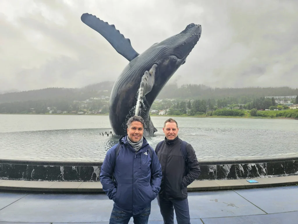 Cruising with Danny and Peter, Holland America Line, Westerdam, Juneau, Alaska, United States | Boat approaching Sentinel Island Lighthouse during Alaska whale watching tour, with humpback whale and stunning coastal scenery in the background.